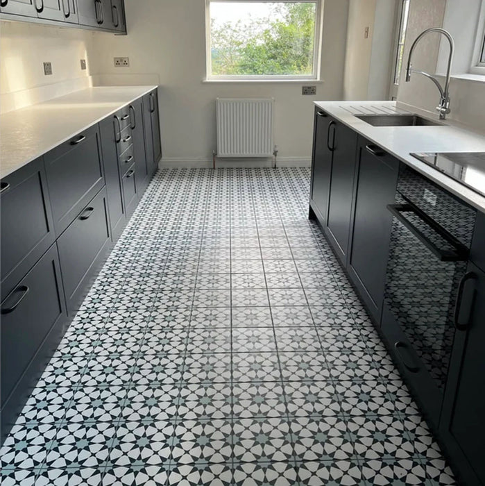 Cocina con azulejos cerámicos de estilo marroquí Agraba Azul Blue 20x20 cm para suelo, con patrón geométrico de estrellas en tonos azul marino, combinados con mobiliario gris oscuro, encimeras blancas y detalles cromados para un contraste moderno.