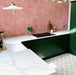 Azulejos de estilo marroquí Alhambra Palacio 20x20 cm en una cocina moderna con mobiliario en verde oscuro, encimeras efecto mármol y azulejos hexagonales rosados en la pared, creando un contraste elegante con el suelo geométrico decorativo.