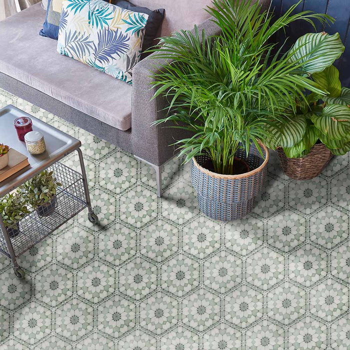 Baldosas hexagonales Maroush Verde 18,7x21,6 cm de estilo marroquí utilizadas en un salón, con patrón floral geométrico en verde suave y blanco, combinadas con sofá gris y plantas en maceta para un ambiente fresco y elegante.