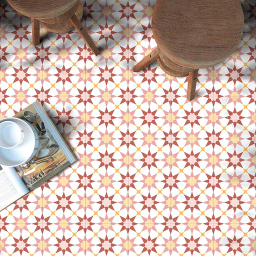 Espacio estilo cafetería con azulejos cerámicos de estilo marroquí Agraba Primavera 20x20 cm para suelo en tonos terracota cálido, melocotón y blanco, combinados con taburetes de madera y una revista abierta para un ambiente mediterráneo relajado.