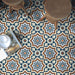 Brompton Grand 20x20cm Victorian-Moroccan-style ceramic floor tiles in a marketing setting, featuring intricate star and floral patterns in navy blue, white, and terracotta tones, styled with wooden stools and an open magazine on the floor.