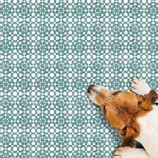 Azulejos de estilo marroquí Bedouin Tetuan Verde 15x15 cm en un ambiente lifestyle con un perro descansando sobre la superficie decorada, mostrando intrincados motivos geométricos de estrellas y cruces en verde suave y blanco roto con acabado mate artesanal.