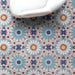 Interior setting featuring Fizaan Fiera 20x20cm Moroccan-style porcelain floor tiles, showcasing a bold geometric pattern in soft blue, red and neutral tones, styled with a modern white chair.