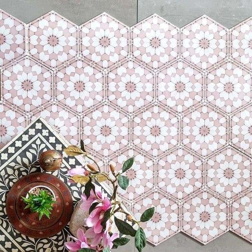 Baldosas hexagonales Maroush Rosa Empolvado 18,7x21,6 cm de estilo marroquí en composición flat lay, mostrando el detallado patrón floral geométrico en rosa y blanco junto a elementos decorativos y flores.