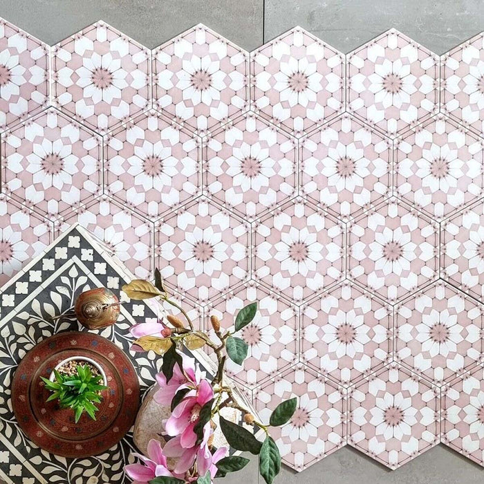 Baldosas hexagonales Maroush Rosa Empolvado 18,7x21,6 cm de estilo marroquí en composición flat lay, mostrando el detallado patrón floral geométrico en rosa y blanco junto a elementos decorativos y flores.