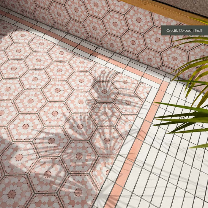 Zona de estar exterior con azulejos hexagonales Maroush Dusty Pink de 18,7 × 21,6 cm de estilo marroquí, instalados tanto en el suelo como en los asientos de obra, con un elaborado patrón geométrico en rosa y blanco y azulejos de borde a juego.