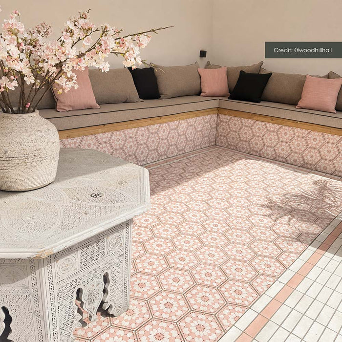 Zona de estar exterior con azulejos hexagonales Maroush Dusty Pink de 18,7 × 21,6 cm de estilo marroquí, instalados tanto en el suelo como en los asientos de obra, con un elaborado patrón geométrico en rosa y blanco y azulejos de borde a juego.