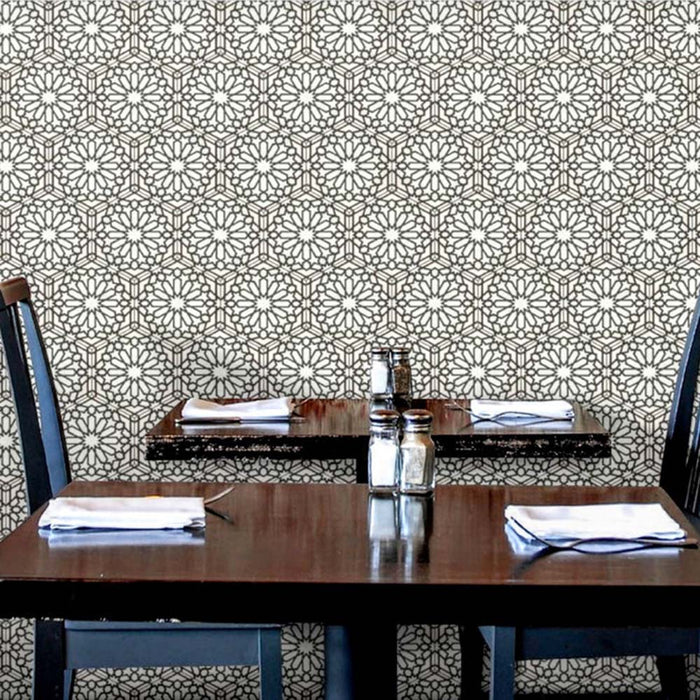 Interior de restaurante con azulejos cerámicos de estilo marroquí Alhambra Hexagon 18,7x21,6 cm para pared, mostrando un patrón geométrico en blanco y negro dispuesto en composición hexagonal repetida detrás de mesas de madera.