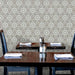 Interior de restaurante con azulejos cerámicos de estilo marroquí Alhambra Hexagon 18,7x21,6 cm para pared, mostrando un patrón geométrico en blanco y negro dispuesto en composición hexagonal repetida detrás de mesas de madera.