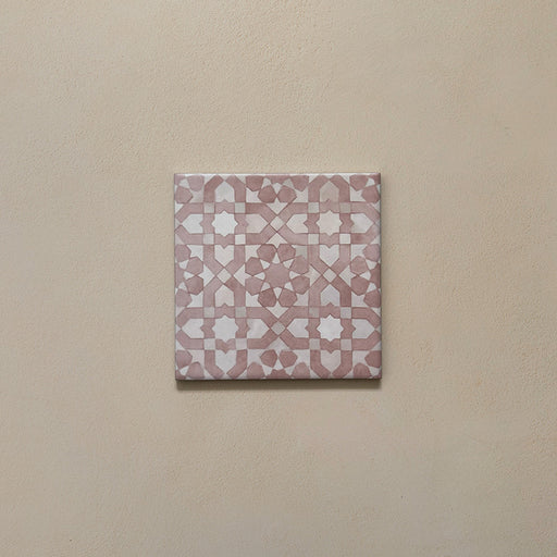 Azulejo individual de estilo marroquí Bedouin Tetuan Rosa 15x15 cm con intrincado patrón geométrico en tonos rosa empolvado y blanco suave, presentado sobre fondo neutro cálido para resaltar el acabado mate artesanal y la textura sutil.