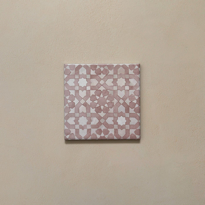 Azulejo individual de estilo marroquí Bedouin Tetuan Rosa 15x15 cm con intrincado patrón geométrico en tonos rosa empolvado y blanco suave, presentado sobre fondo neutro cálido para resaltar el acabado mate artesanal y la textura sutil.