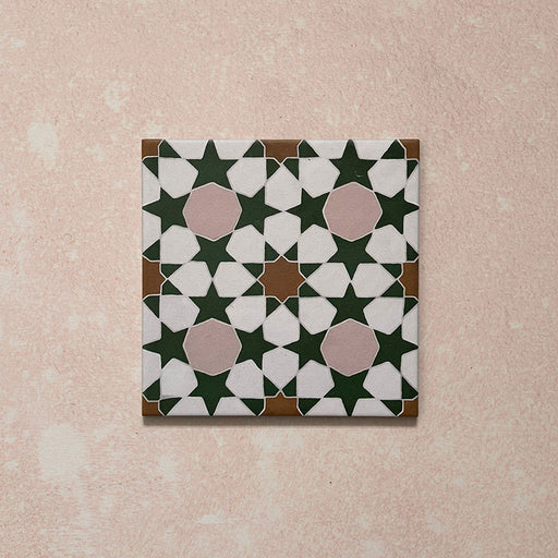Azulejo porcelánico individual de estilo marroquí Agraba Tanane 20x20 cm con patrón geométrico de estrellas y cruces en verde intenso, rosa suave, blanco y tonos tierra, con acabado mate liso.