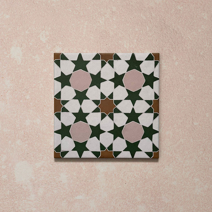 Azulejo porcelánico individual de estilo marroquí Agraba Tanane 20x20 cm con patrón geométrico de estrellas y cruces en verde intenso, rosa suave, blanco y tonos tierra, con acabado mate liso.