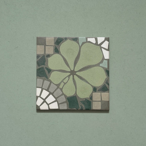 Baldosa Nantes Verde 20x20 cm de estilo marroquí mostrada individualmente, con patrón floral en tonos verde suave, gris y blanco sobre fondo verde, presentada en primer plano.