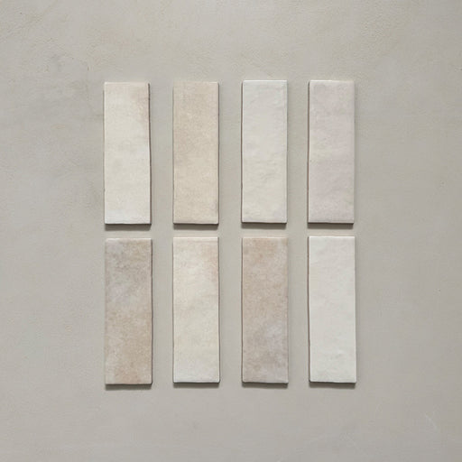 Vista cenital de azulejos de pared cerámicos Zellij Ocre Ladrillo 6,5 × 20 cm de estilo marroquí, presentados como piezas individuales, destacando la variación tonal suave, los bordes ligeramente irregulares y el acabado brillante artesanal en tonos neutros cálidos sobre un fondo liso.