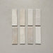 Vista cenital de azulejos de pared cerámicos Zellij Ocre Ladrillo 6,5 × 20 cm de estilo marroquí, presentados como piezas individuales, destacando la variación tonal suave, los bordes ligeramente irregulares y el acabado brillante artesanal en tonos neutros cálidos sobre un fondo liso.