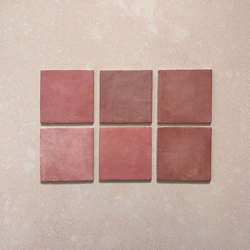 Vista cenital de azulejos de pared cerámicos Zellij Rosa Ladrillo 6,5 × 20 cm de estilo marroquí, presentados como piezas individuales, destacando la variación tonal suave, los bordes ligeramente irregulares y el acabado brillante artesanal en tonos rosados sobre un fondo texturizado.