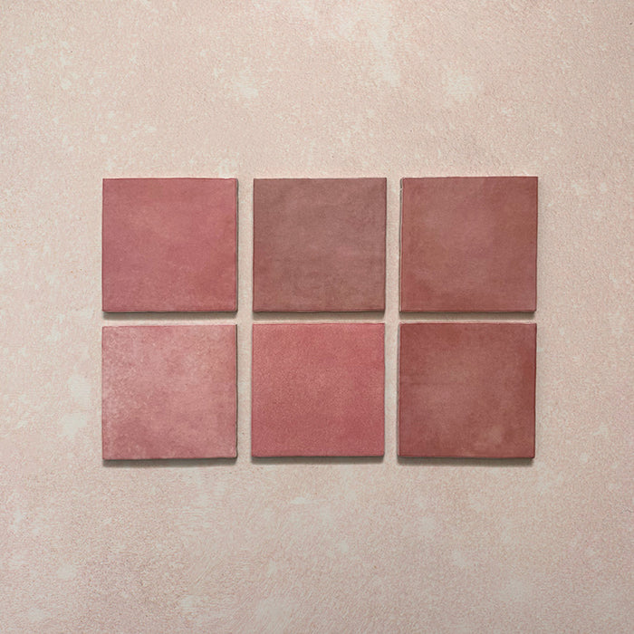 Vista cenital de azulejos de pared cerámicos Zellij Rosa Ladrillo 6,5 × 20 cm de estilo marroquí, presentados como piezas individuales, destacando la variación tonal suave, los bordes ligeramente irregulares y el acabado brillante artesanal en tonos rosados sobre un fondo texturizado.
