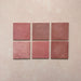 Vista cenital de azulejos de pared cerámicos Zellij Rosa Ladrillo 6,5 × 20 cm de estilo marroquí, presentados como piezas individuales, destacando la variación tonal suave, los bordes ligeramente irregulares y el acabado brillante artesanal en tonos rosados sobre un fondo texturizado.