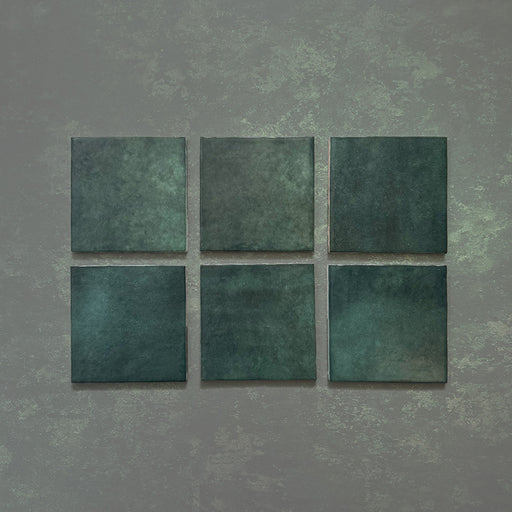 Vista cenital de azulejos de pared cerámicos Zellij Verde Musgo Cuadrado 13,2 × 13,2 cm de estilo marroquí, presentados como piezas individuales, destacando la rica variación en tonos verdes, el acabado brillante artesanal y los bordes suavemente irregulares para un aspecto auténtico y lleno de carácter.