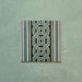 Single Europa Toulouse 20x20cm Victorian Moroccan style border tile displayed against a textured green background, featuring a decorative interlocking geometric pattern in green, grey and cream tones.