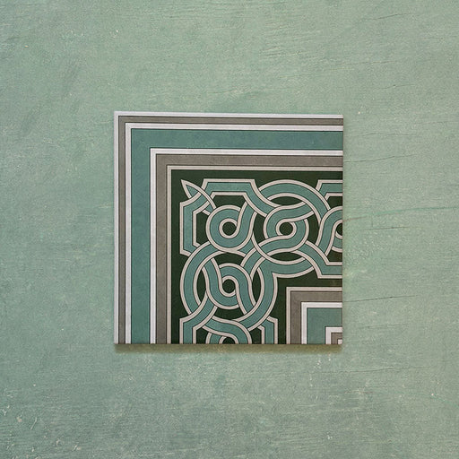Single Europa Toulouse Corner 20x20cm Victorian Moroccan style tile displayed against a textured green background, featuring a decorative corner border design in green, grey and cream tones.