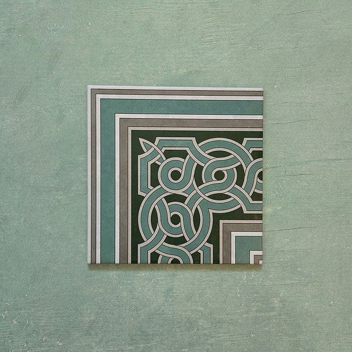 Single Europa Toulouse Corner 20x20cm Victorian Moroccan style tile displayed against a textured green background, featuring a decorative corner border design in green, grey and cream tones.