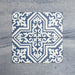 Cuatro baldosas Europa Trondheim Blue 20 × 20 cm de estilo Victoriano Marroquí colocadas juntas para mostrar el patrón decorativo repetitivo en tonos azul y blanco, sobre un fondo gris texturizado.