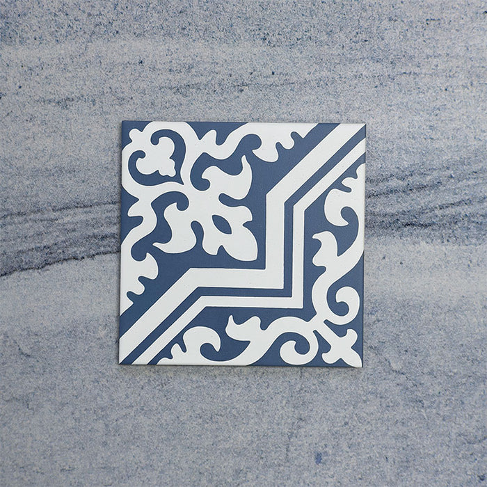 Baldosa Europa Trondheim Blue 20 × 20 cm de estilo Victoriano Marroquí mostrada individualmente sobre un fondo gris texturizado, con un patrón geométrico y floral decorativo en tonos azul y blanco en una imagen de producto en primer plano.