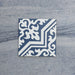 Baldosa Europa Trondheim Blue 20 × 20 cm de estilo Victoriano Marroquí mostrada individualmente sobre un fondo gris texturizado, con un patrón geométrico y floral decorativo en tonos azul y blanco en una imagen de producto en primer plano.