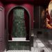 Baño de estilo atrevido con azulejos cuadrados de pared Zellij Moss Green de 13,2 × 13,2 cm, con intensas variaciones de tonos verdes, combinados con paredes en color burdeos, cortinas de terciopelo, paneles decorativos oscuros, obras de arte y un suelo con motivos geométricos en blanco y negro.