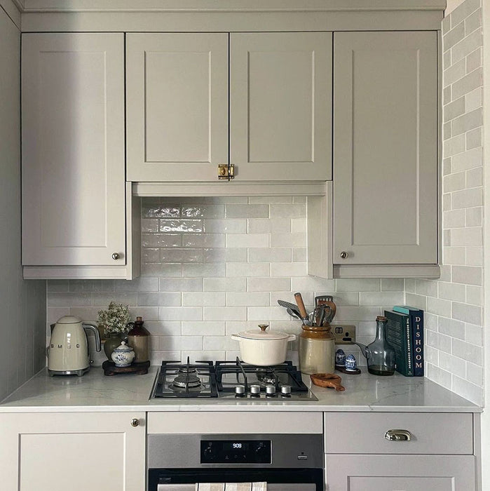 Cocina tradicional con azulejos de pared cerámicos Zellij White Brick 6,5 × 20 cm de estilo marroquí, mostrando una suave variación tonal y una textura brillante de aspecto artesanal, combinados con mobiliario estilo shaker, encimeras con efecto mármol y decoración en tonos neutros.