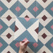 Cabana Guazzatto 20x20cm Moroccan-style porcelain tile featuring a bold geometric cross design in blue, cream, pink, and burgundy shades with a smooth matt finish.