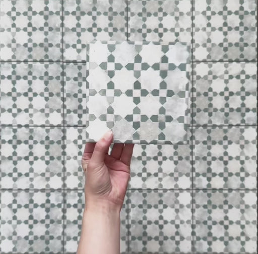 Vídeo de los azulejos de estilo marroquí Bedouin Mequinez Verde 15x15 cm, resaltando su patrón geométrico de estrellas y cruces en verde, gris y blanco, con efecto envejecido artesanal y sutil textura superficial.